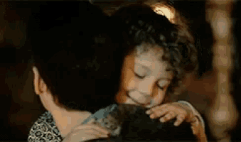 a man is hugging a woman who is holding a cell phone .