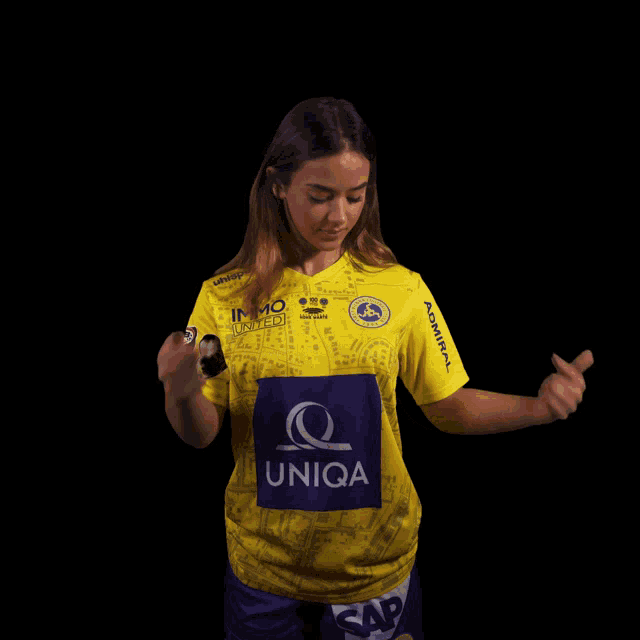 a woman wearing a yellow shirt with the word uniqa on the front