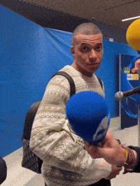 a man with a backpack is holding a blue microphone in front of a blue background