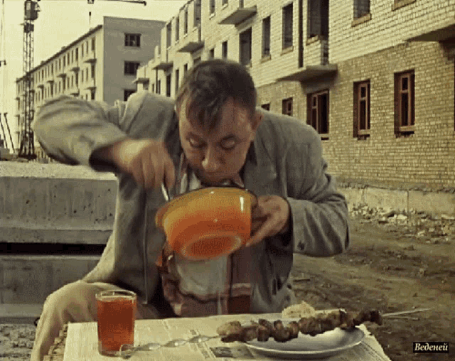 a man is sitting at a table with a plate of food and a cup of tea with the word bedenei on the bottom right