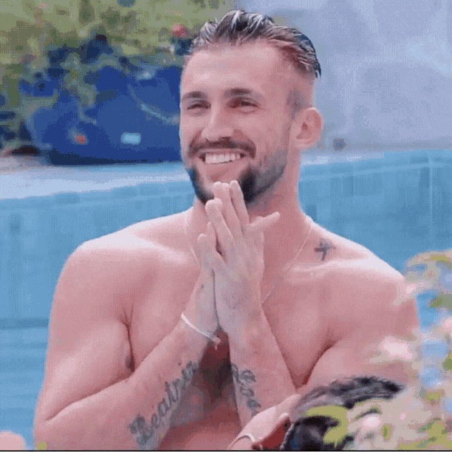 a shirtless man with a tattoo on his arm that says beatriz is smiling and clapping his hands .