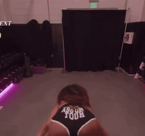 a woman is doing a butt flip in a gym while wearing shorts that say ass your