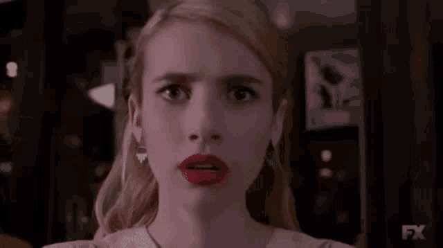 a woman with red lipstick is making a funny face .