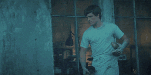 a man in a white shirt is standing in front of a window