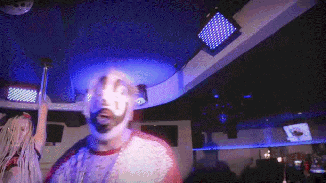 a man in a clown mask is dancing in a dark room