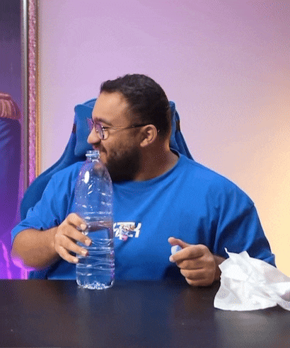 a man in a blue shirt is drinking from a plastic bottle
