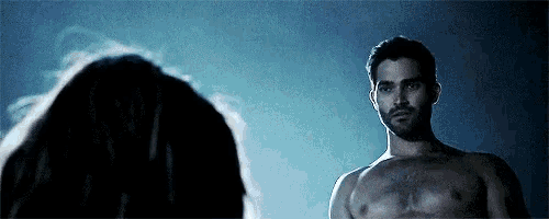 a shirtless man is standing next to a woman in the dark .