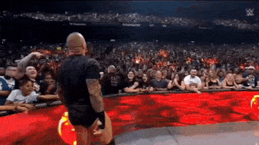 a man in a black shirt is standing in front of a crowd of people in a stadium .