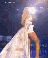 a woman in a long white dress is standing on a stage .