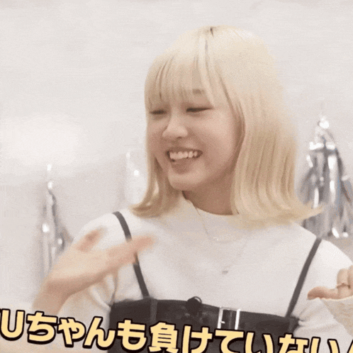 a girl with blonde hair is laughing with the word shizuku in yellow letters