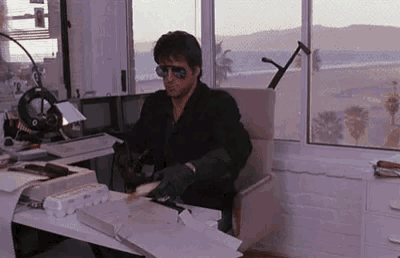 a man is sitting at a desk in front of a window .