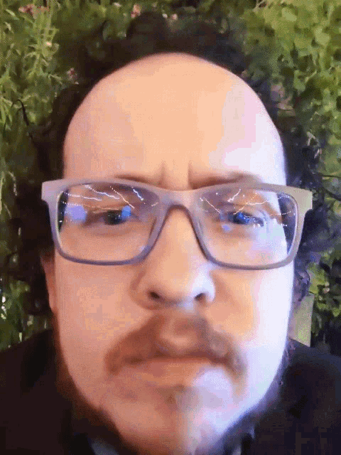 a man with glasses and a beard is looking at the camera