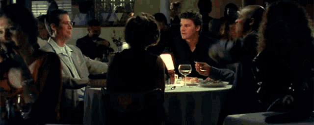 a man in a blue shirt is holding another man 's hand in a dark room with a light coming out of it .