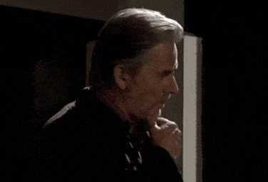 a man with a beard is standing in a dark room and looking at the camera .