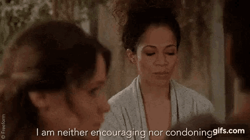 a woman in a bathrobe is talking to a man in a room while another woman looks on .