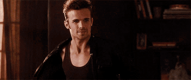 a man in a black tank top is taking off his jacket