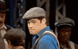 a man wearing a hat and a blue shirt is standing in front of a group of men .