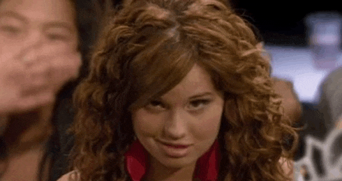 a woman with curly hair is making a funny face in front of a crowd of people .