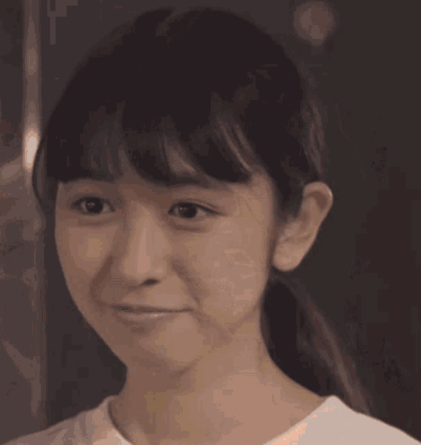 a young girl is smiling and making a funny face with her eyes closed .