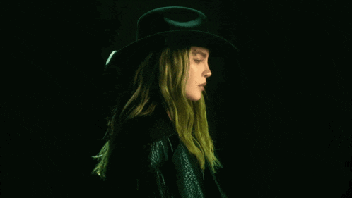 a woman with long hair wearing a black hat and a black jacket