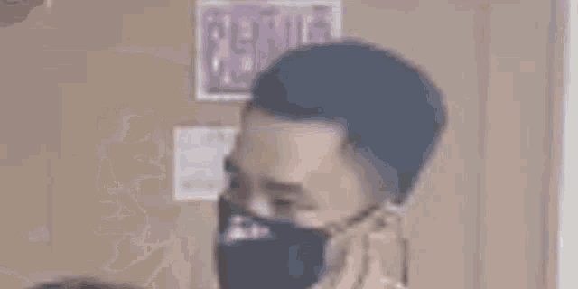 a man is holding a gun to his face in front of a bulletin board .