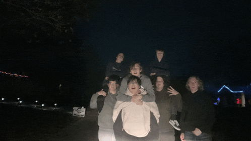 a group of young men are posing for a picture and one of them is carrying another on his back