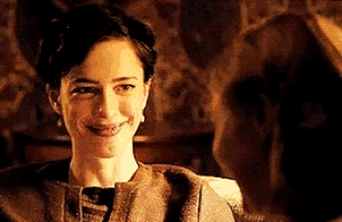 a woman is smiling while sitting in a chair with a man behind her .