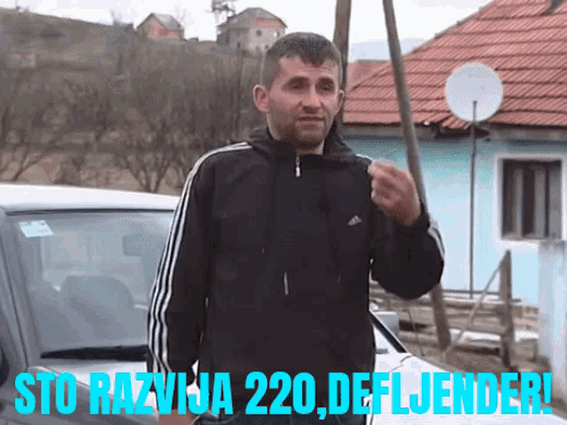 a man in a black adidas jacket is standing in front of a car