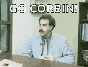 a man in a suit and tie is sitting at a desk with the words `` go corbin '' written on it .