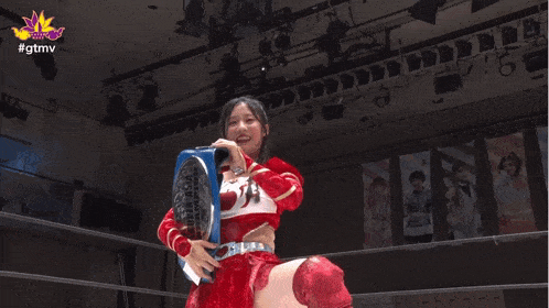 a woman in a red top is holding a super asia champion belt over her head