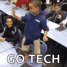 a young boy is standing on a chair in a classroom while a group of children sit at tables .