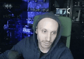 a bald man wearing a hoodie is sitting in a chair