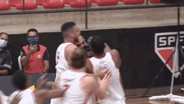 a group of basketball players are hugging each other in front of a wall that says sp