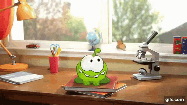 a cartoon character is sitting on a desk next to a microscope and a book .