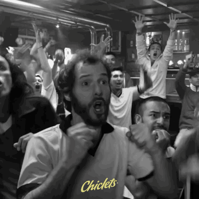a man wearing a shirt that says chiclets is surrounded by people