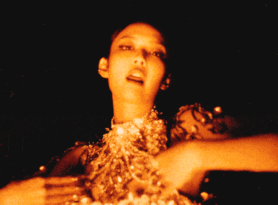 a woman with a necklace on her neck is surrounded by fire