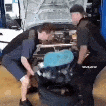 a couple of men are working on a car engine .