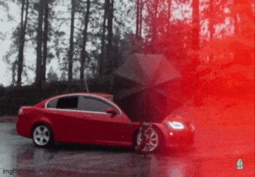 a red car with its hood open and a black umbrella in the rain .