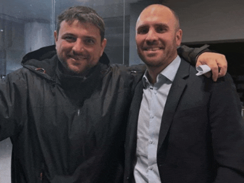 two men posing for a picture with one wearing a jacket