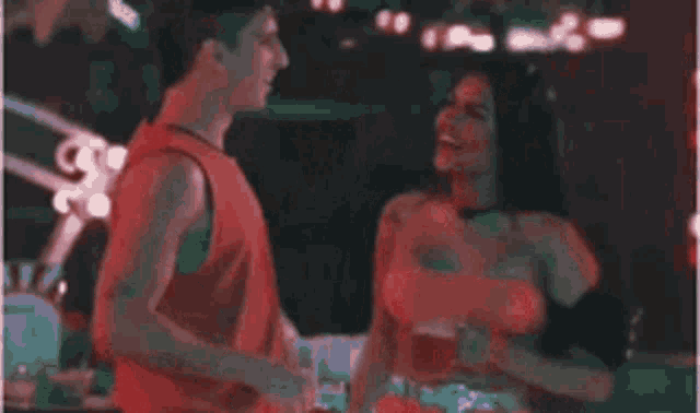 a man and a woman are standing next to each other in a nightclub .