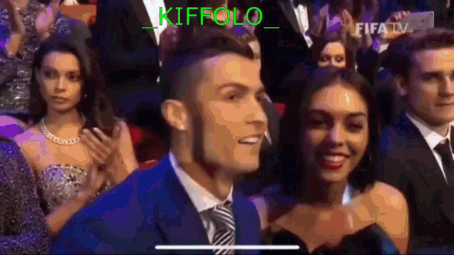a man in a suit and tie is looking at a woman in a dress in a crowd .