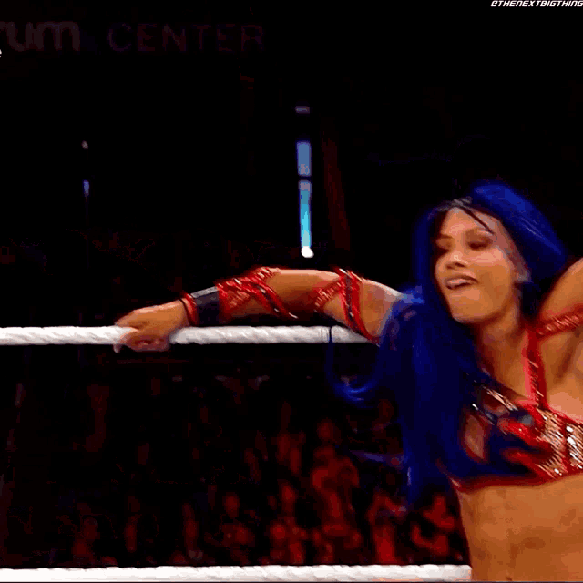 a woman with blue hair is standing in a wrestling ring with a w logo on her hat