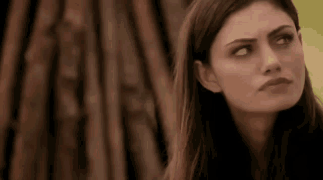 a close up of a woman 's face with a wooden background