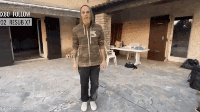 a man with a beard is standing in front of a house with a sign that says " x80 follow "