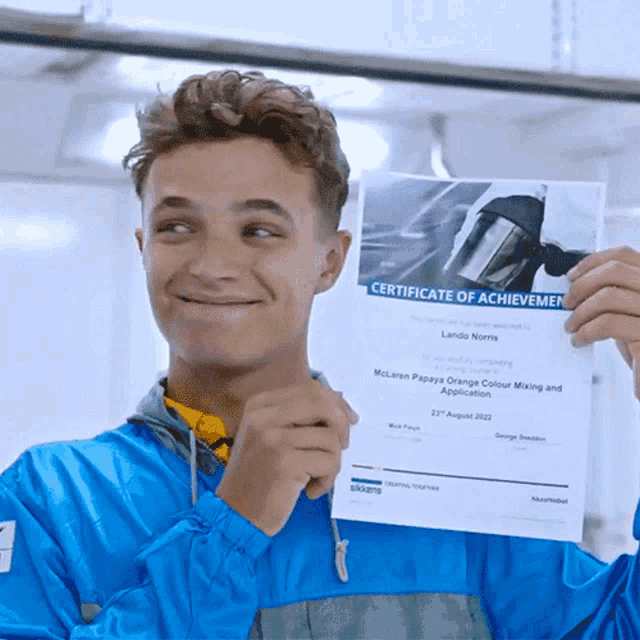 a young man is holding up a certificate of achievemen