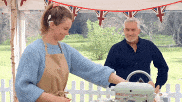 a man and a woman are standing next to a mixer