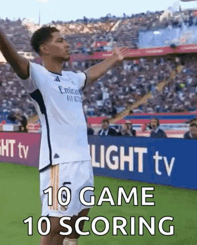 a soccer player is standing on a soccer field with his arms outstretched and says `` 10 game 10 scoring '' .
