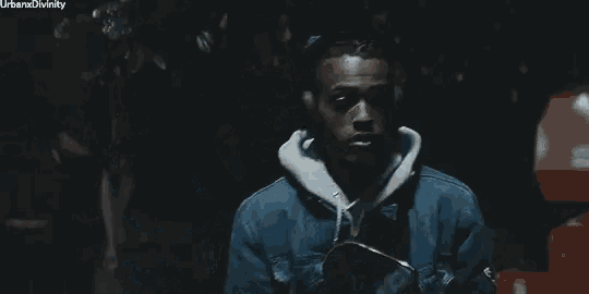 a man in a denim jacket and headphones is standing next to a woman in a dark room .