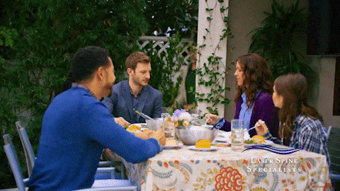 a family sits at a table with a table cloth that says laser spine specialists on it