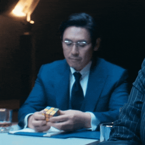 a man in a suit and tie is holding a rubik 's cube